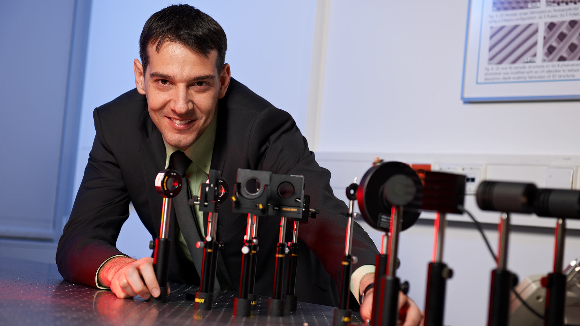 Portrait eines Wissenschaftlers zusammen mit einem Versuchsaufbau im Laserlabor.