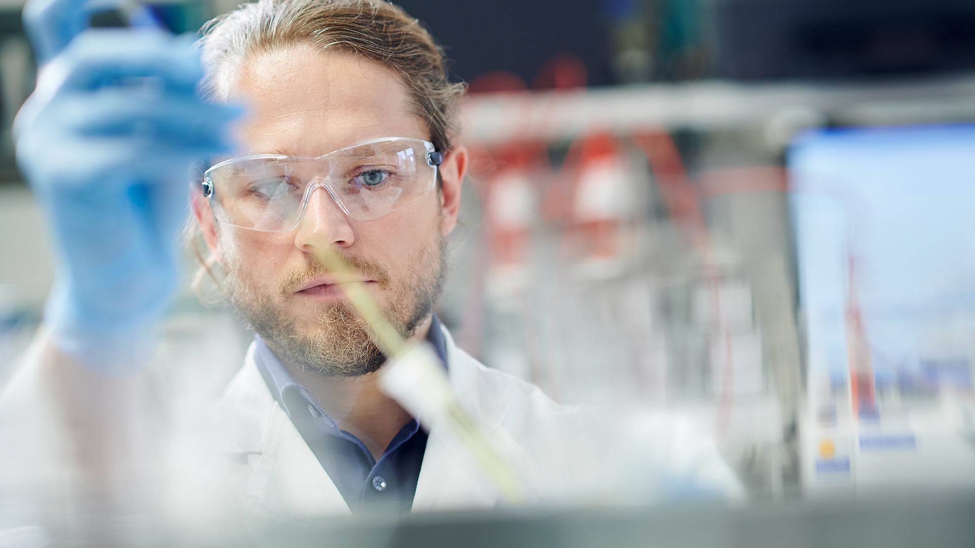 Konzentrierter Blick eines Labormitarbeiters beim Pipettieren. Industriefoto für die Imagekampagne der Organica Feinchemie.